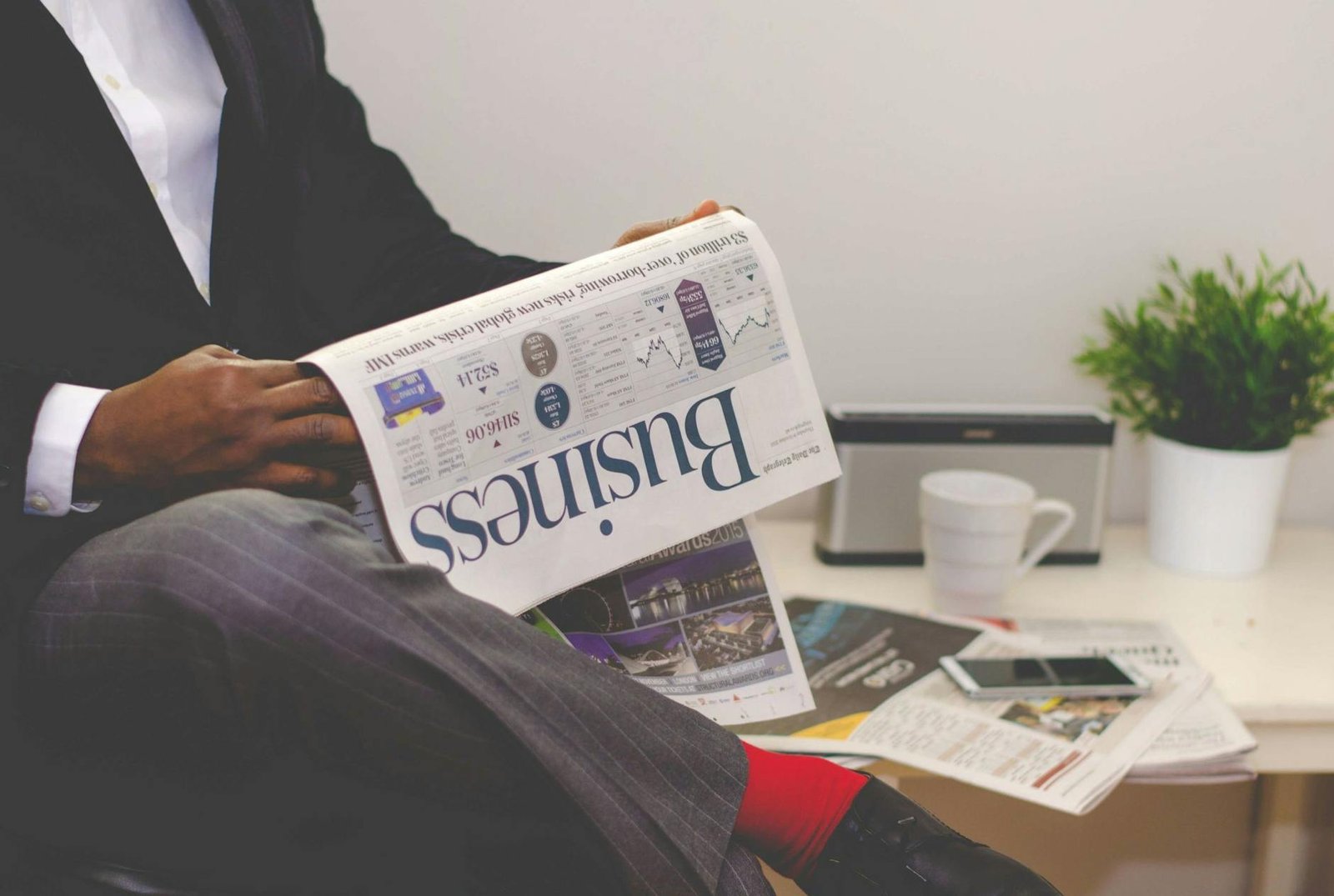 How to Protect Your Finances - Finance - man reading newspaper while sitting near table with smartphone and cup man reading newspaper while sitting near table with smartphone and cup